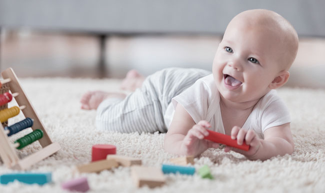 caregiver feeding happy young infant at the table with a spoon